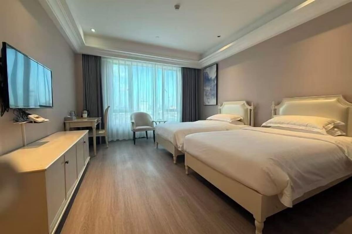 Een hotelkamer met twee bedden, een bureau, een stoel en een televisie.