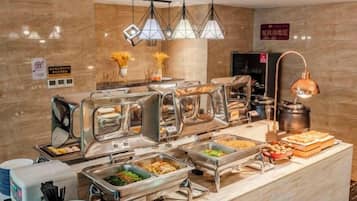 A buffet setup with multiple food service stations, a coffee machine, and a decorative lamp.