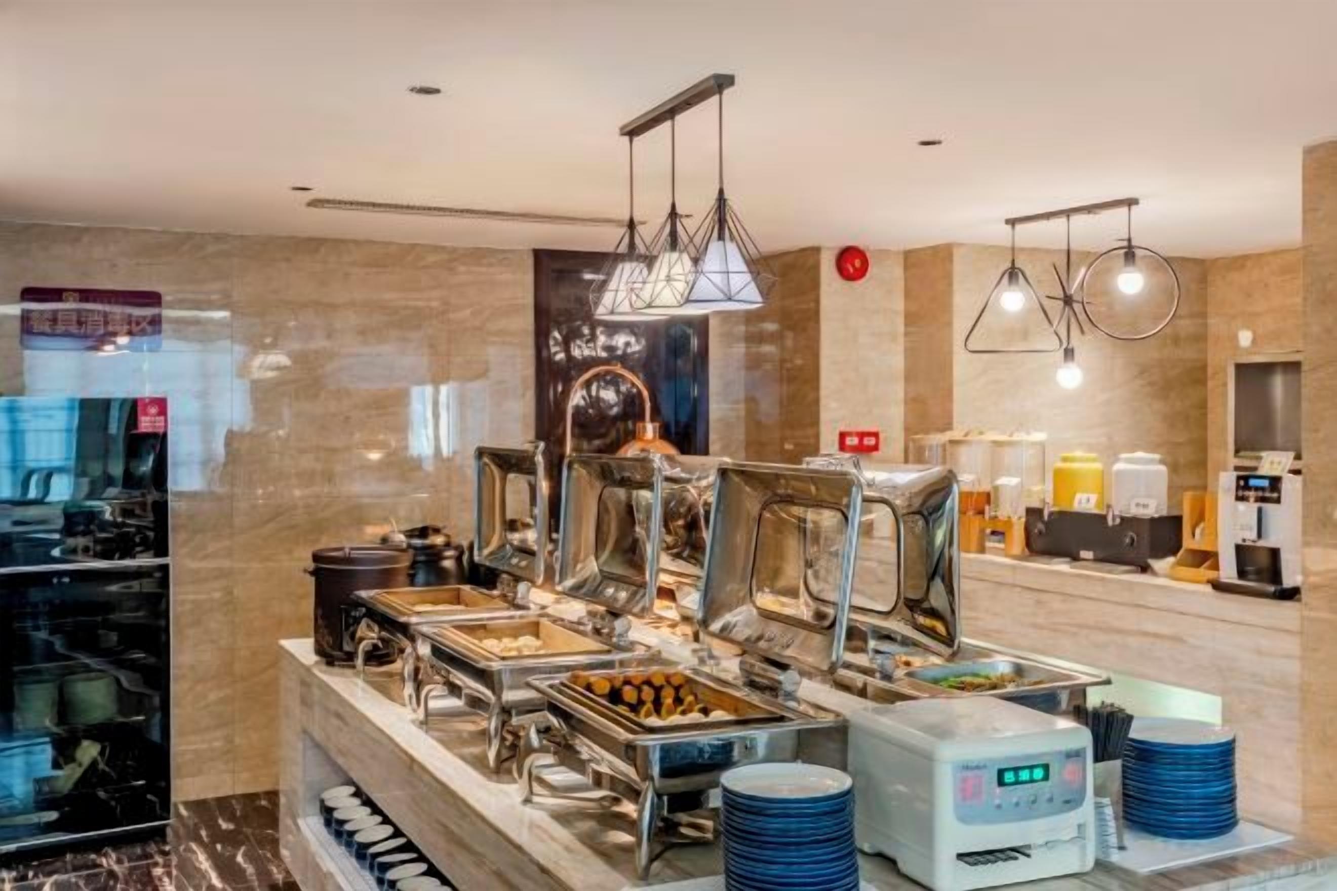 Zona de buffet amb diferents punts de menjar, una màquina de cafè i una zona de seients amb barra.