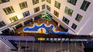 Un hôtel à plusieurs étages, doté d’une cour intérieure avec une fontaine et d’une enseigne indiquant « SkyLine Hotel ».