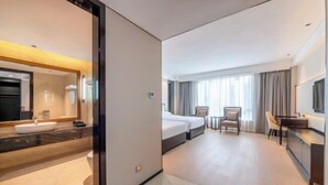 Une chambre d’hôtel avec salle de bain, un lit, un bureau et un téléviseur.