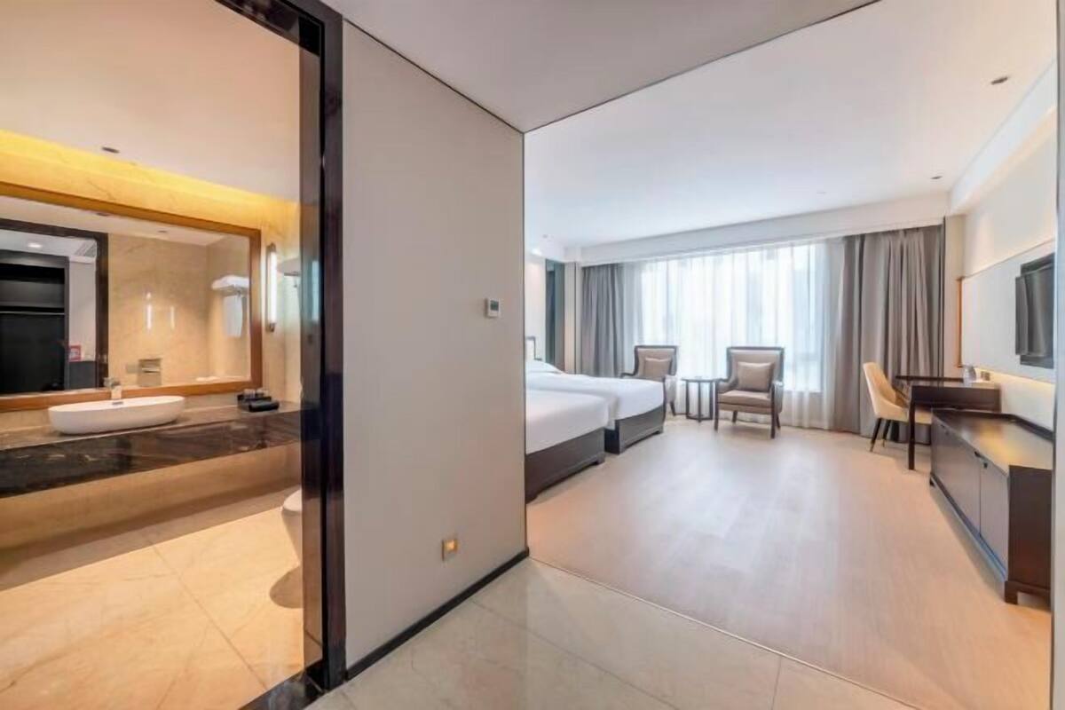 Een hotelkamer met een badkamer, een bed, een bureau en een televisie.