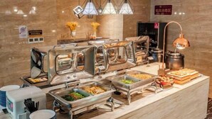 Un buffet avec plusieurs présentoirs de nourriture, une machine à café et une lampe décorative.