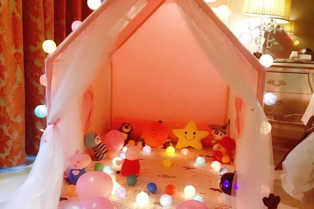 Une pièce chaleureuse, aménagée comme une tente, et décorée de guirlandes lumineuses colorées et de peluches.