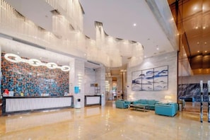 A spacious lobby with a reception desk, seating area, and a large wall with a patterned design. - Tianyi International Hotel (Zhongshan Tanzhou Commercial Center) (Zhongshan)