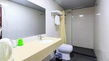 A bathroom with a sink, mirror, toilet, and shower.