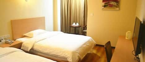 A hotel room with two beds, a desk, a chair, a television, and a window with curtains.