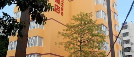 A multi-story building with a yellow facade and red signage.