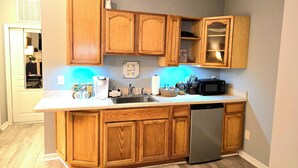 A kitchen with wooden cabinets, a stainless steel dishwasher, and a microwave. - The secret Manor (Durham)
