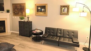 A living room with a sofa, a small table, a lamp, a fireplace, and framed artwork on the wall. - The secret Manor (Durham)