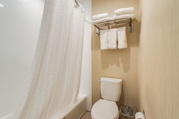 A bathroom with a bathtub, toilet, and a towel rack with folded towels. - Oceanus Motel (Rehoboth Beach)