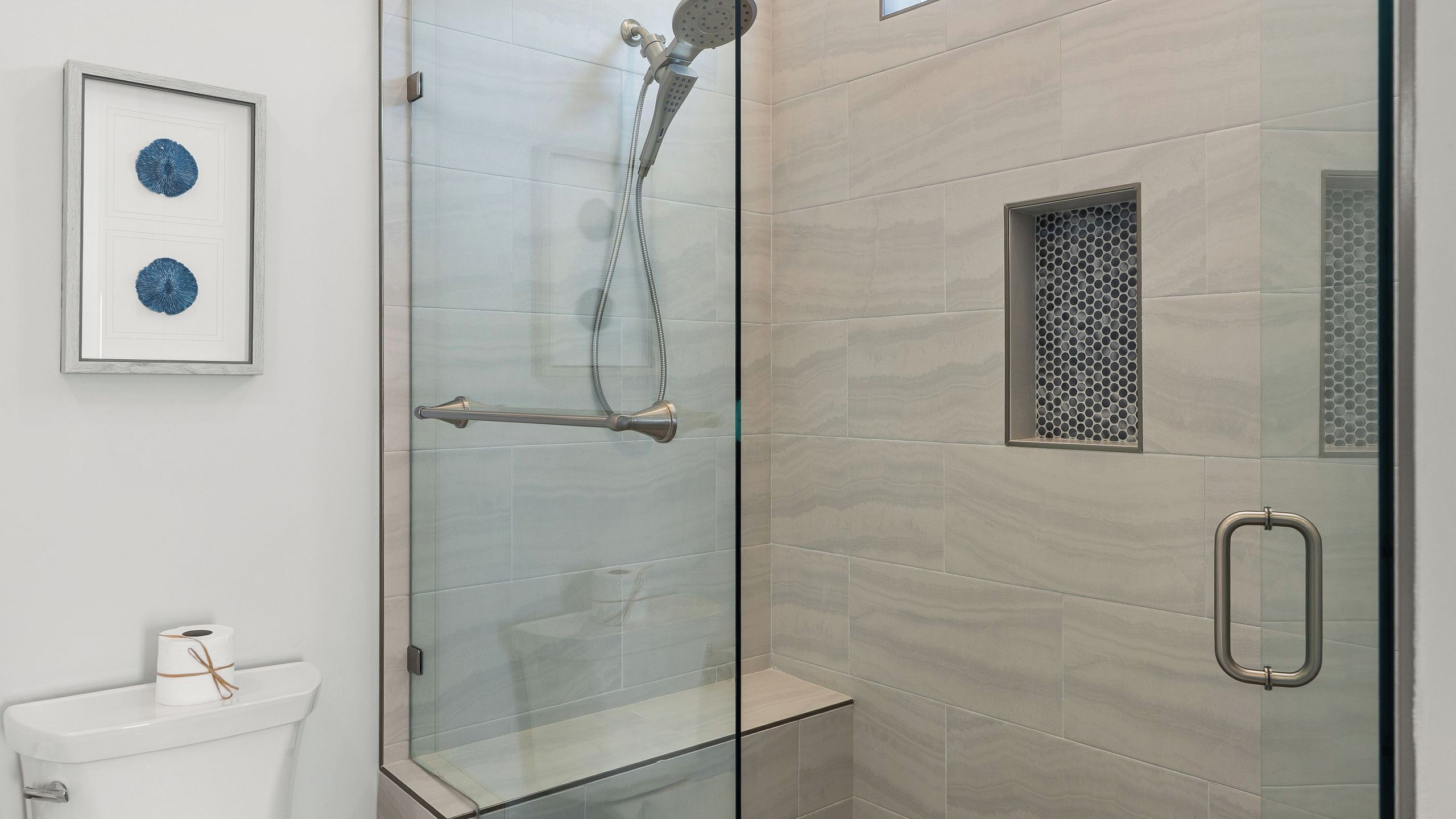 Ein modernes Badezimmer mit Duschkabine aus Glas, Toilette und einem gerahmten Kunstwerk an der Wand.