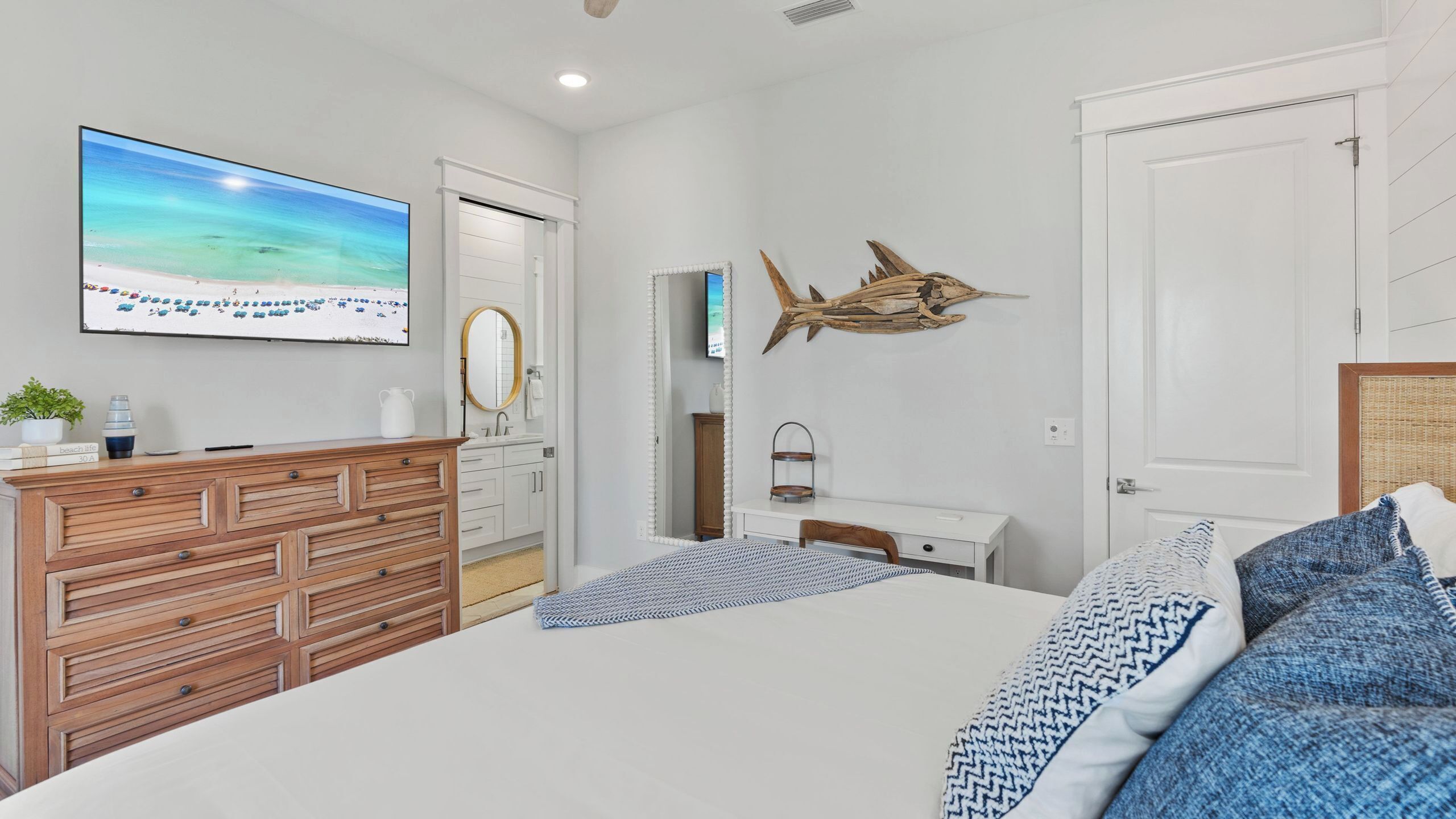 A bedroom with a bed, dresser, TV, and a wall-mounted mirror.