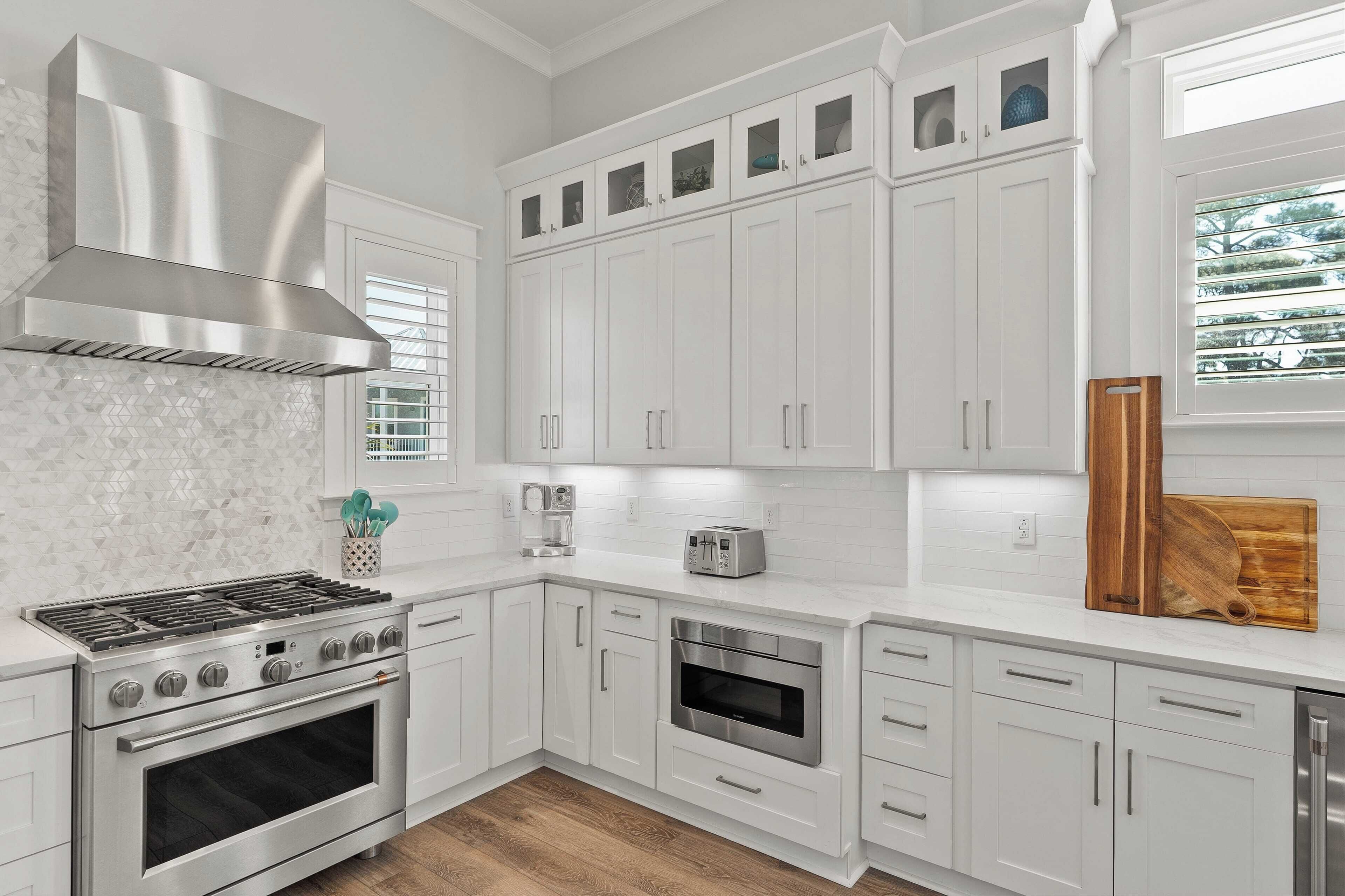 A modern kitchen with white cabinetry, a stainless steel range, and an oven.