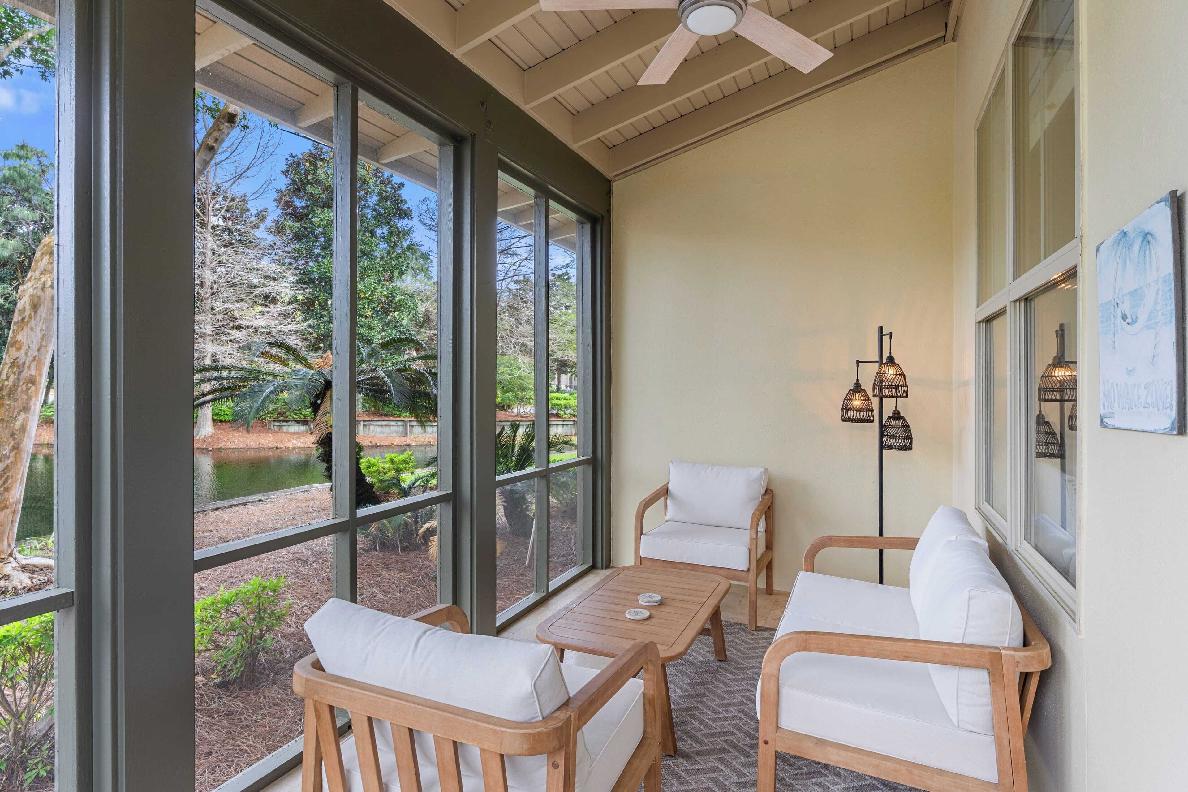 A sunroom with large windows, wooden furniture, and a ceiling fan.