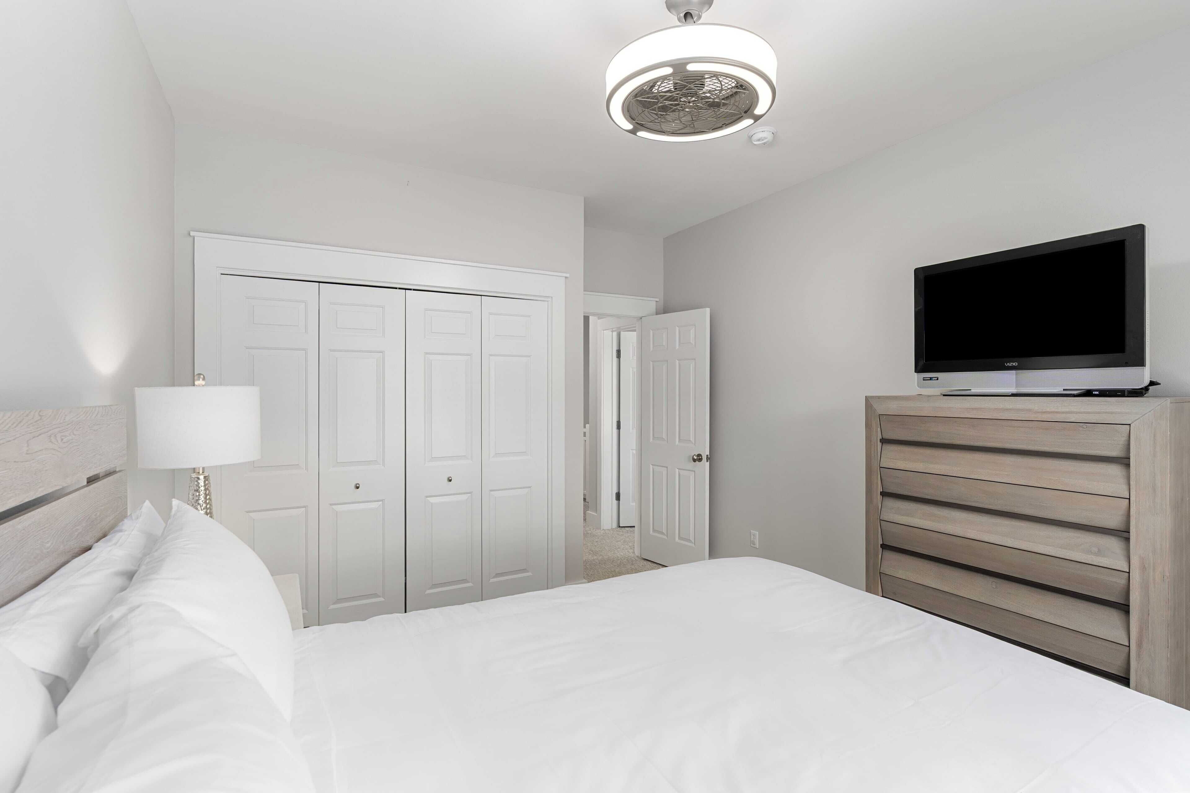 A hotel room with a bed, a TV, a wardrobe, and a ceiling light.