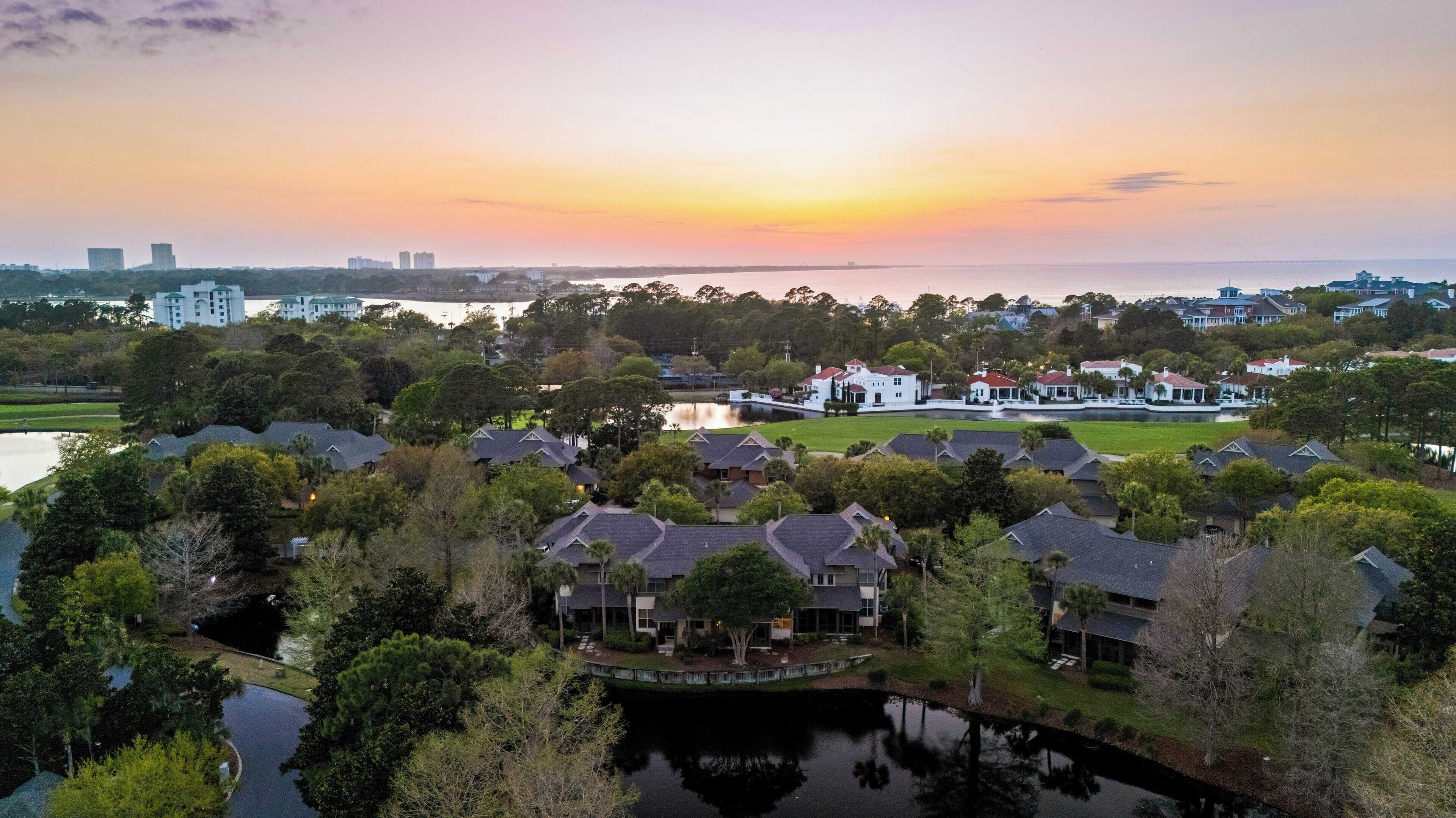 A residential area with houses, a large white building, and a body of water.