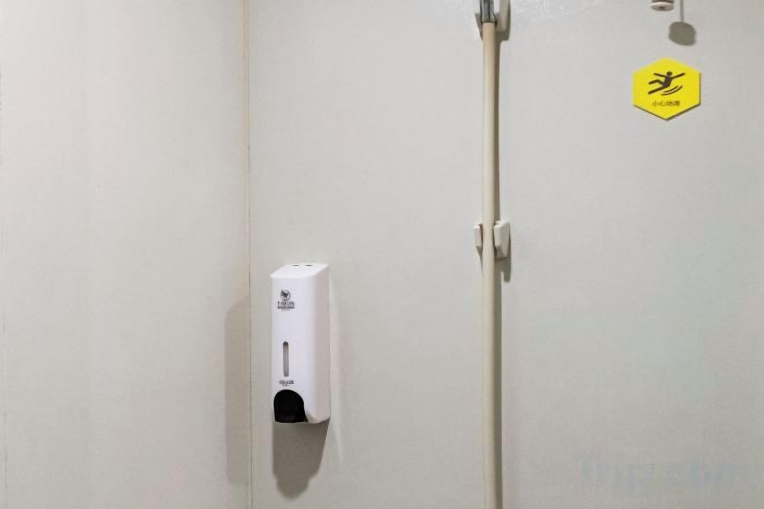A door with a hand sanitizer dispenser mounted on the wall and a sign with a symbol.