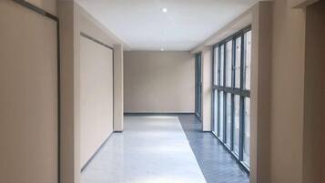 A corridor with a polished floor, large windows, and a plain wall.