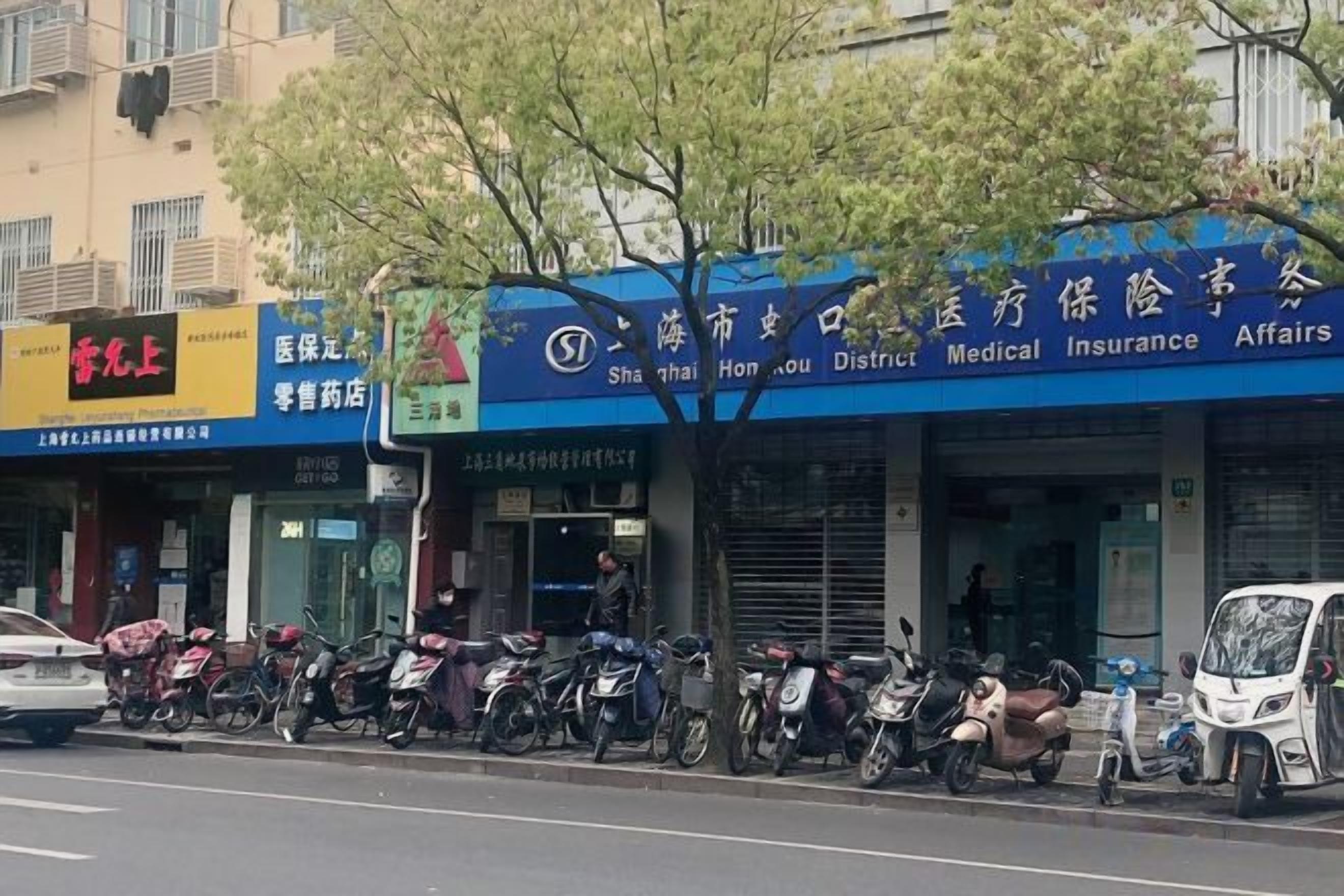 A street view with a medical insurance office, a pharmacy, and several parked motorcycles.