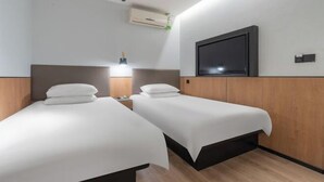 Een hotelkamer met twee bedden, een aan de muur bevestigde televisie en een bedlampje.