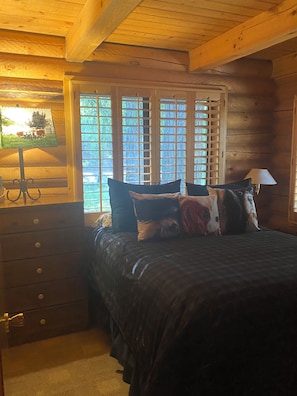 Relax in this serene bedroom with a large bed, wooden shutters, and a bedside lamp.