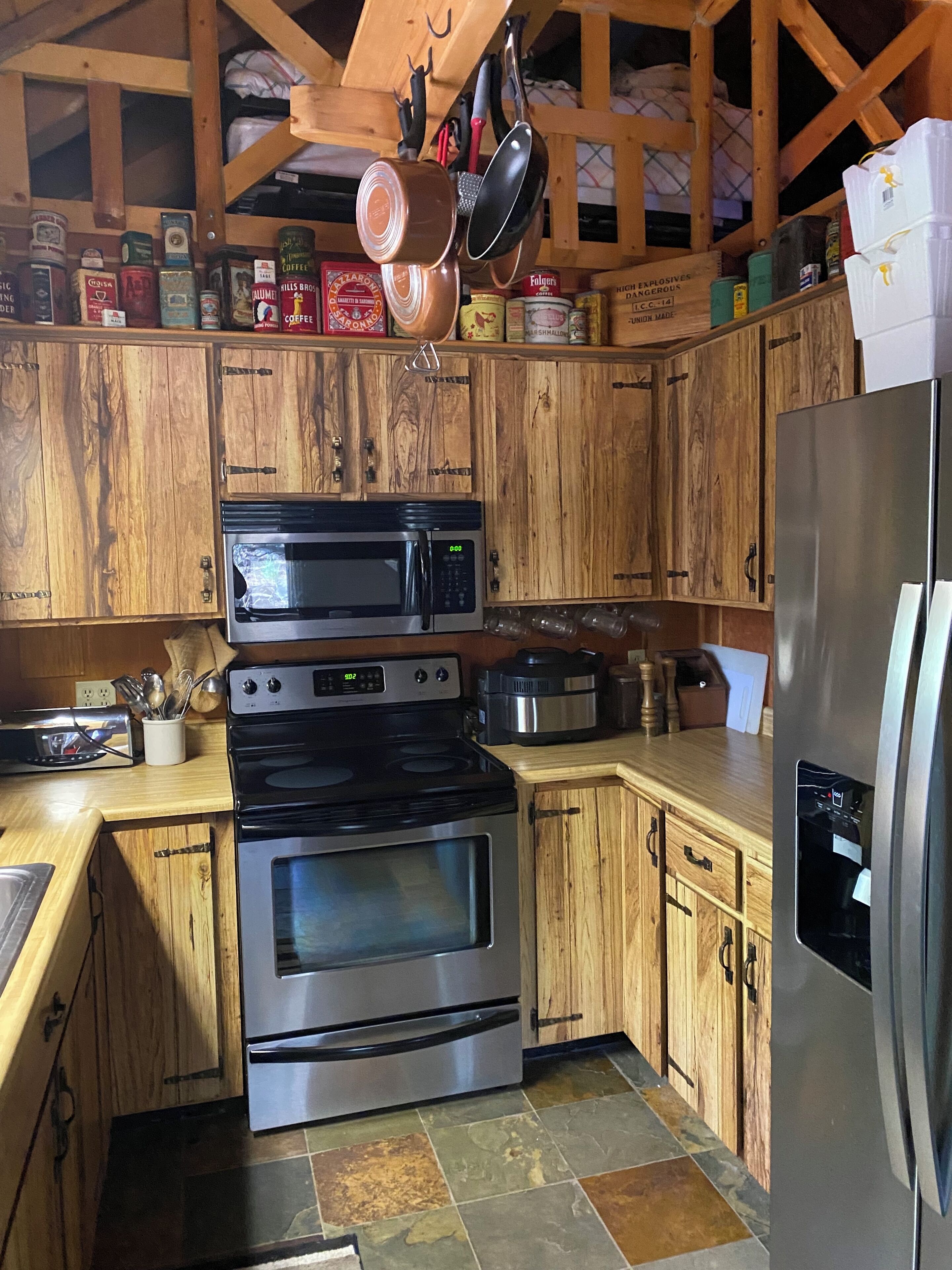 A kitchen with wooden cabinets, stainless steel appliances, and a variety of food items on shelves.