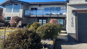 Ein modernes, zweistöckiges Haus mit Balkon, Garage und einem gepflegten Garten.