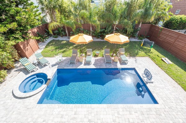Relax by the pool surrounded by lush greenery and comfortable lounge chairs.