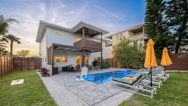 Une maison moderne à deux étages, dotée d’une piscine, d’un espace salon extérieur et d’un patio couvert.