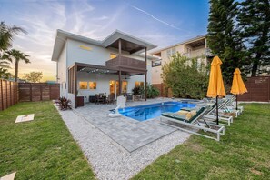 A modern two-story house with a swimming pool, outdoor seating, and a covered patio area. - Beach Luxury | Pool, Spa, Steam Shower, Game Room (St. Augustine)