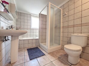 Une salle de bain avec un lavabo, des toilettes, une douche et une petite fenêtre.