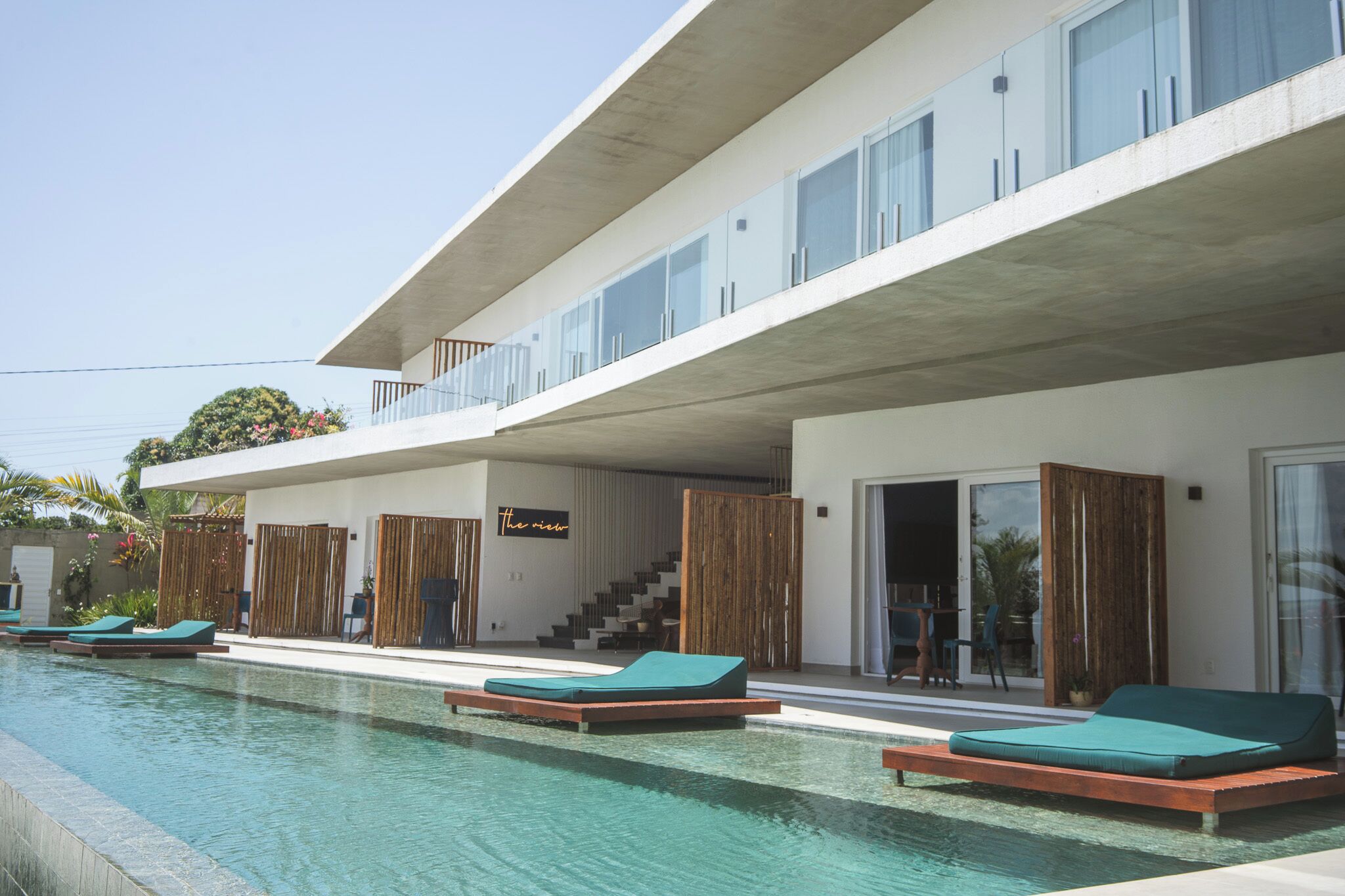 Un edificio moderno con piscina, poltrona relax e una scala che porta a un balcone.