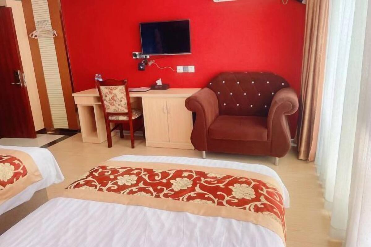Habitación de hotel con dos camas, un escritorio, una silla, un televisor y un armario.