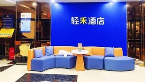 A hotel lobby with a blue wall and a sign reading "轻禾酒店". There is a blue and orange sofa set with a small round table in front. - Light Stay Hotel - Xiaozhu (Shanghai Chuansha Branch) (Shanghai)