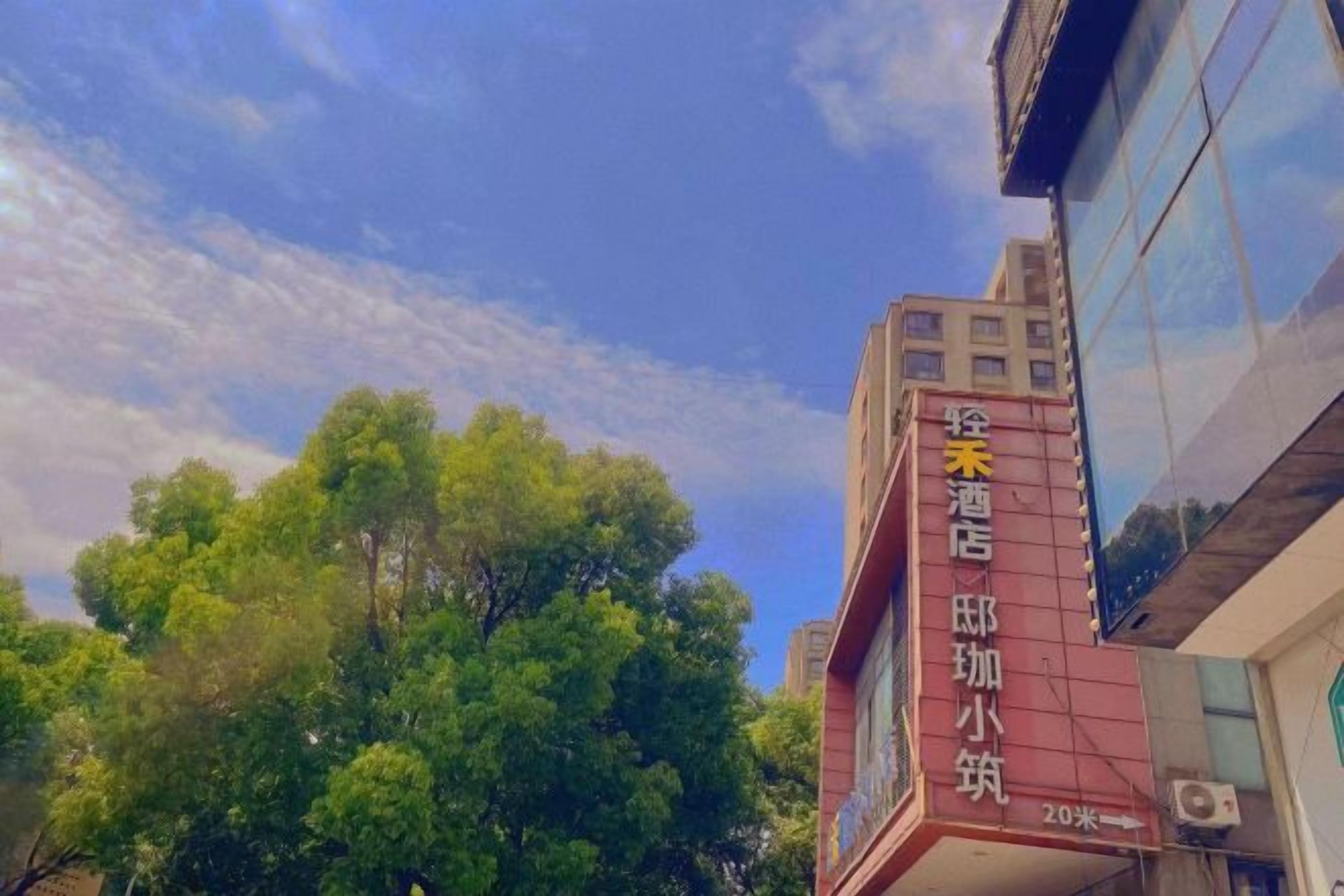 Een hotelschild met Chinese karakters, een heldere lucht en bomen op de achtergrond.