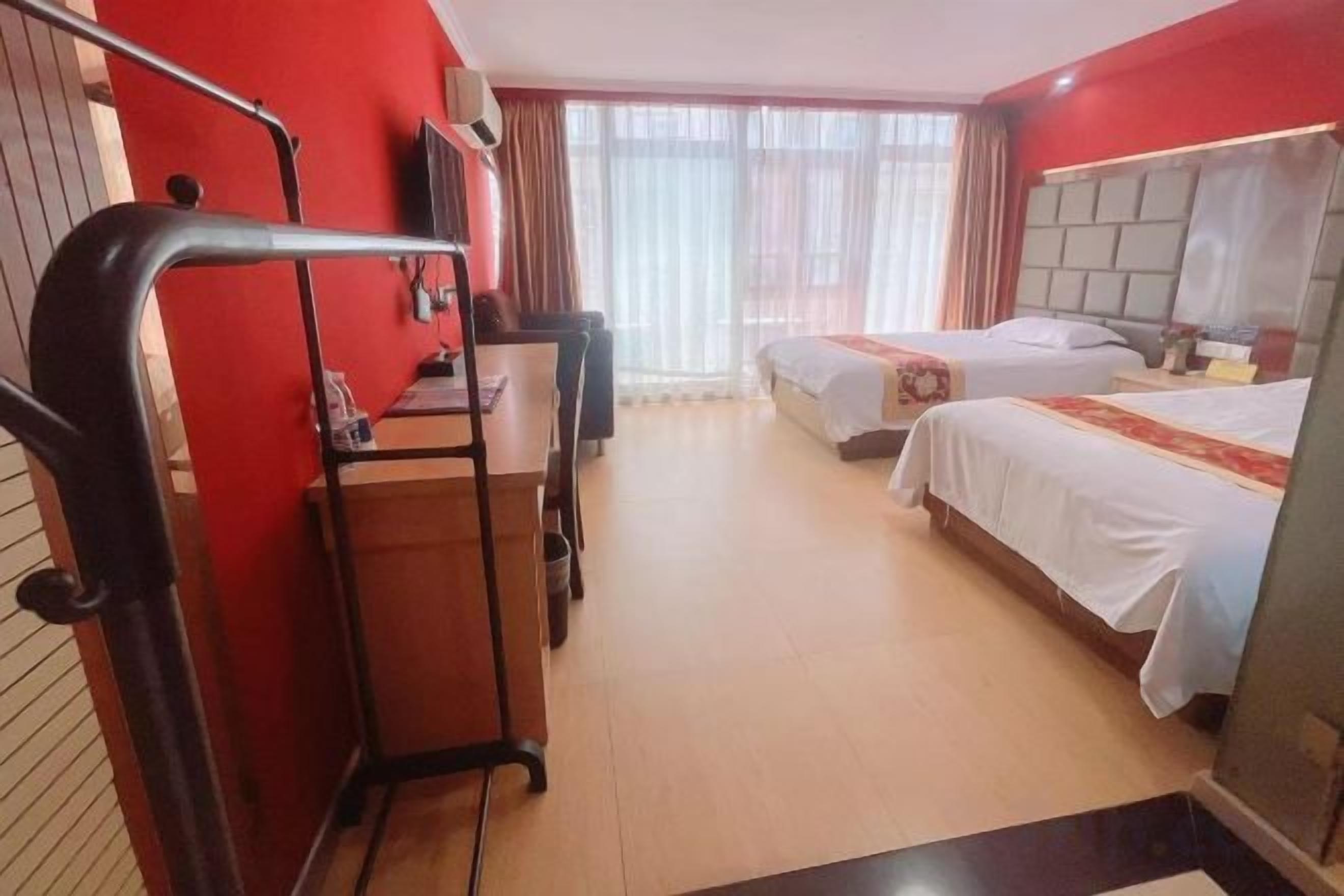 Hotellihuone, jossa on kaksi sänkyä, työpöytä ja tuoli.