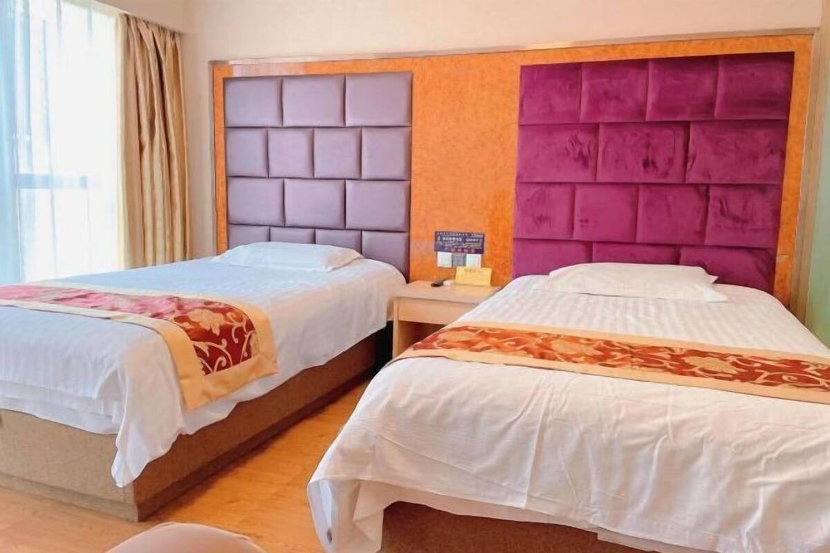 Habitación de hotel con dos camas, cada una con un diseño de cabecera diferente.