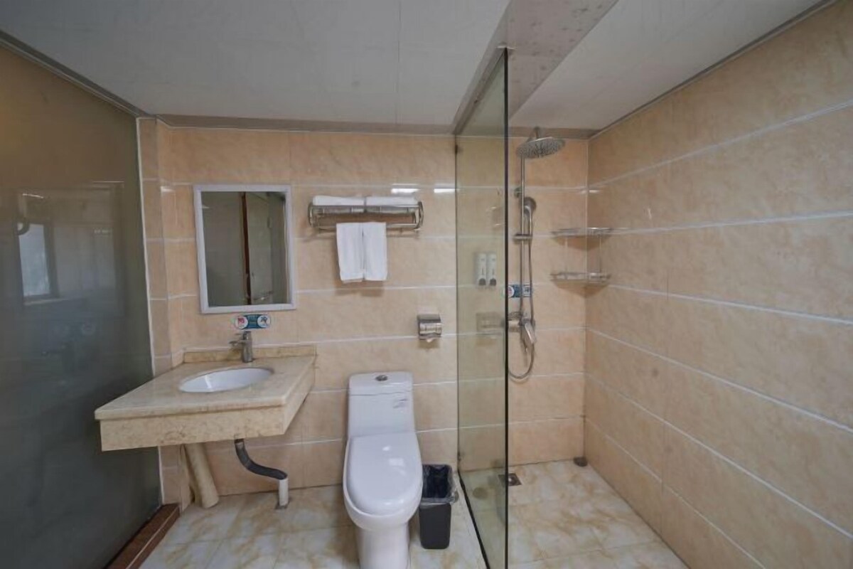 A bathroom with a glass-enclosed shower, a toilet, and a sink with a mirror above it.
