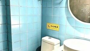 Ein kleines Badezimmer mit blauen Fliesen, einer Toilette und einem Waschbecken.