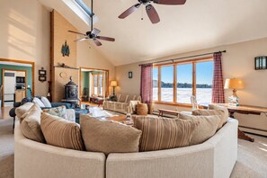Un salón acogedor con chimenea, ventanas amplias y vistas a un paisaje nevado.