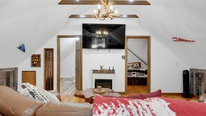 A modern living room with a fireplace, a large mirror, and a ceiling light fixture.