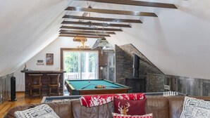 A cozy attic room with a pool table, a bar area, and a fireplace.