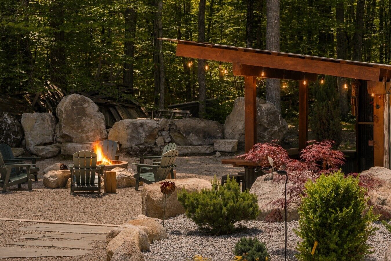 Un espacio exterior acogedor con sillas Adirondack, un pozo de fuego y una pérgola con luces colgantes.