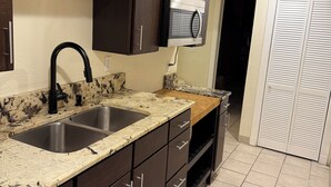 A kitchen with dark wooden cabinets, a double sink, granite countertops, and a built-in microwave.