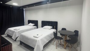 A modern hotel room with two beds, a small dining table, and a chair. - Hotel Gool de Guerrón (Quito)