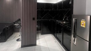 A modern kitchen with a black refrigerator, stainless steel appliances, and a sleek black backsplash. - Hotel Gool de Guerrón (Quito)