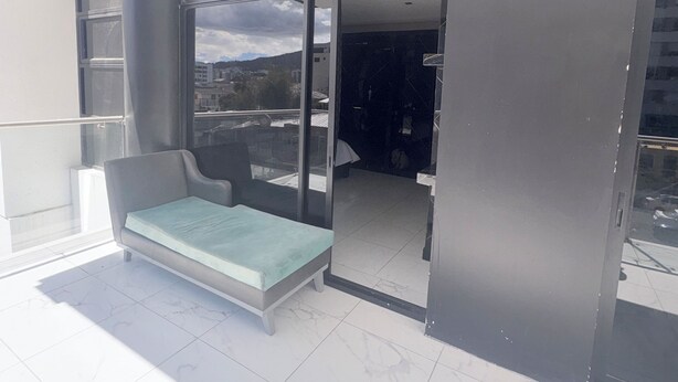 A modern room with a glass door leading to a balcony, a built-in bench, and a view of the cityscape. - Hotel Gool de Guerrón (Quito)