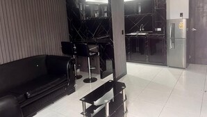 A modern living room with a black leather sofa, a black bar stool, and a glass partition. - Hotel Gool de Guerrón (Quito)