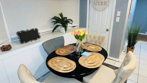 A dining area with a round table, four chairs, and a vase of flowers. - The Suite at North Shore Long Island, Prime Location, Unique and sophisticated (Smithtown)